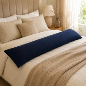 Navy full body pillow lying across a neatly made bed