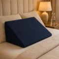 Navy wedge pillow positioned on a bed against the headboard